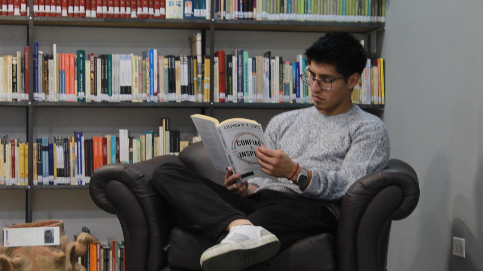 Estudiante leyendo en la sala de lectura de la biblioteca ISPADE