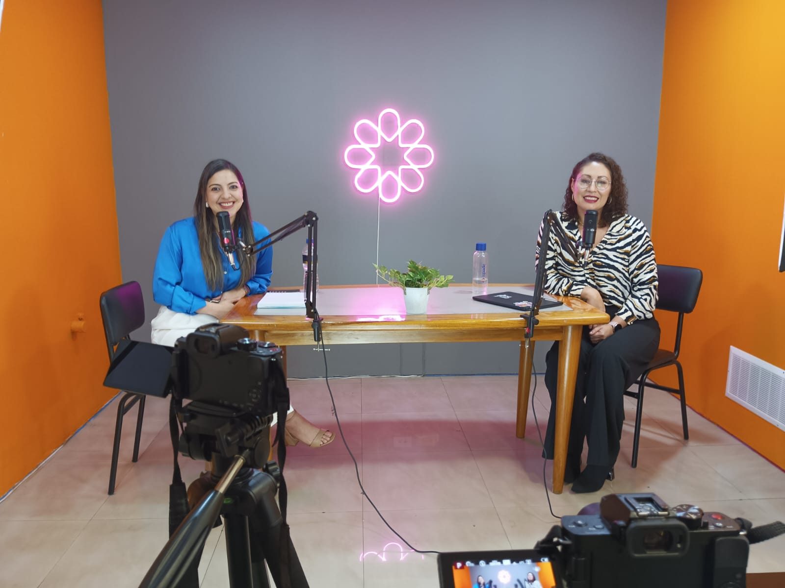 Dos participantes sonríen frente a los micrófonos en el set del podcast Escuchativa