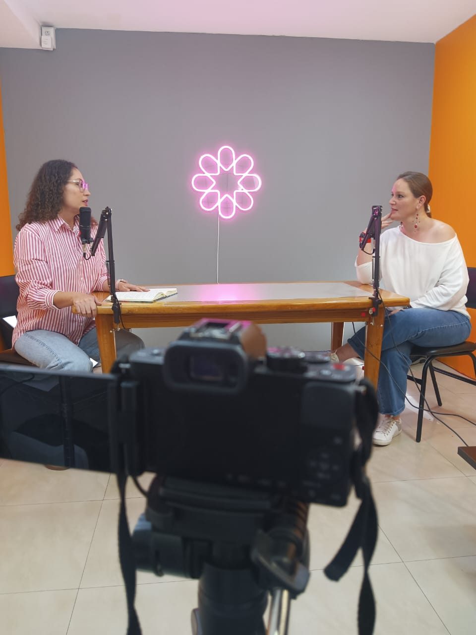 Dos participantes conversan frente a los micrófonos durante la grabación del podcast